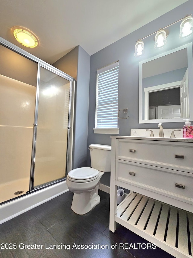 bathroom featuring hardwood / wood-style flooring, vanity, toilet, and a shower with door