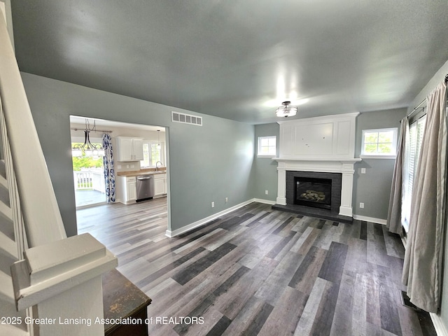 unfurnished living room featuring plenty of natural light, dark hardwood / wood-style floors, and sink