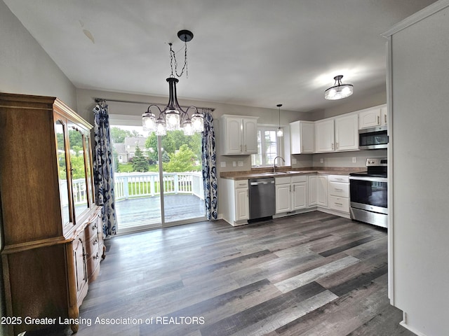 kitchen featuring pendant lighting, sink, hardwood / wood-style floors, stainless steel appliances, and white cabinets