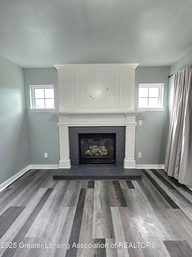 unfurnished living room with dark wood-type flooring, a fireplace, and a healthy amount of sunlight