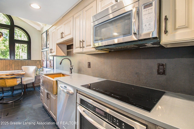 8955 W Braden Rd, Haslett, MI 48840 - kitchen featuring lofted ceiling, sink, stainless steel appliances, tasteful backsplash, and cream cabinetry