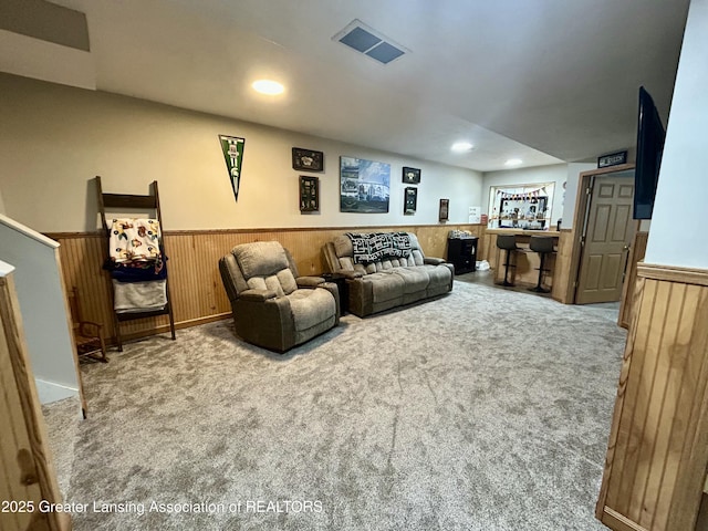 carpeted living room with wood walls