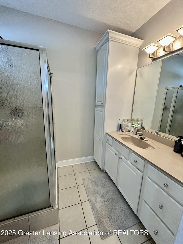 bathroom with tile patterned flooring, vanity, a shower with door, and a textured ceiling