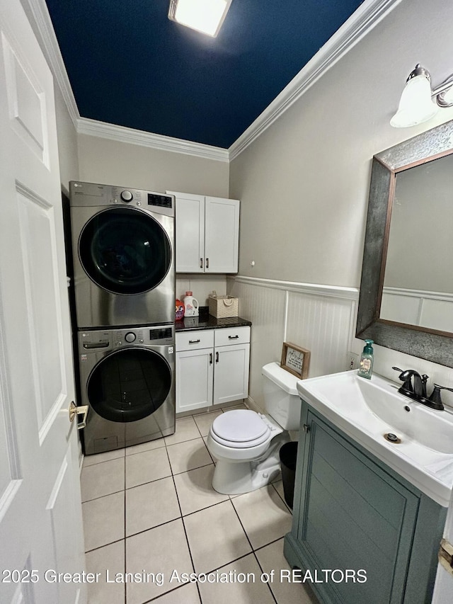 bathroom featuring crown molding, stacked washer / dryer, toilet, and tile patterned flooring