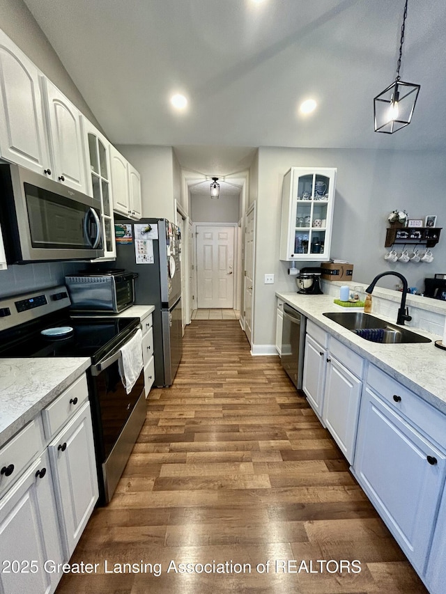 kitchen with sink, decorative light fixtures, dark hardwood / wood-style floors, stainless steel appliances, and white cabinets