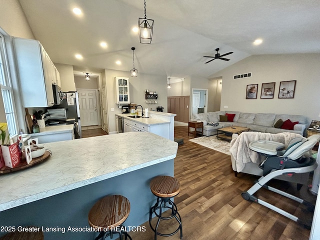 kitchen with sink, hanging light fixtures, appliances with stainless steel finishes, a kitchen breakfast bar, and white cabinets