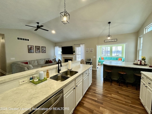 kitchen featuring hanging light fixtures, lofted ceiling, sink, and white cabinets