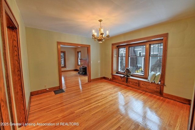 unfurnished dining area with light wood-type flooring and an inviting chandelier