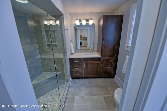 bathroom with toilet, a shower with shower door, vanity, and tile patterned flooring