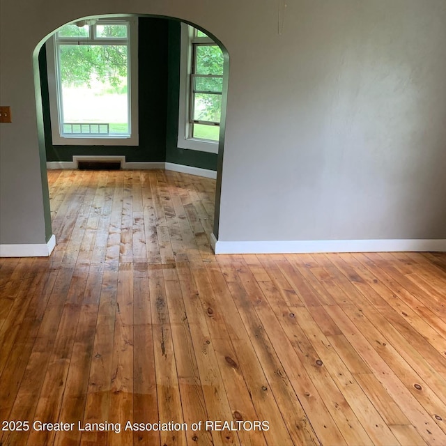 7761 W Herbison Rd, Dewitt, MI 48820 - unfurnished room with arched walkways, wood-type flooring, and baseboards