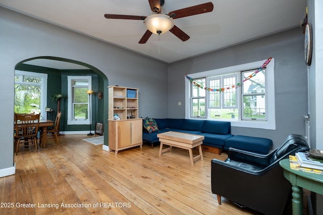 7761 W Herbison Rd, Dewitt, MI 48820 - living room with arched walkways, light wood finished floors, a ceiling fan, and baseboards