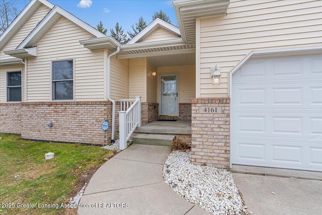 doorway to property featuring an attached garage and brick siding