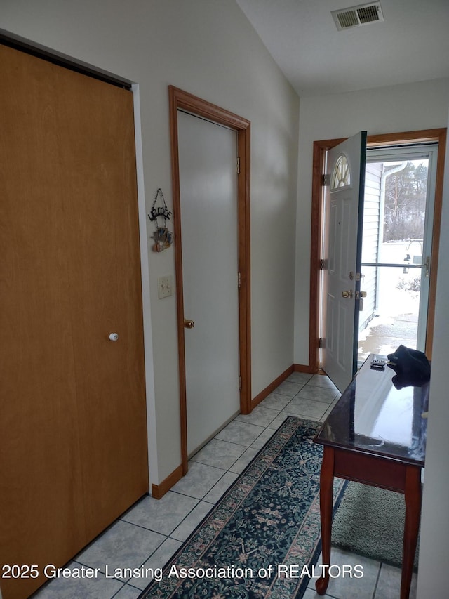 entryway with light tile patterned floors, vaulted ceiling, visible vents, and baseboards