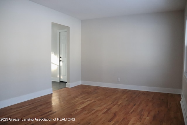 spare room featuring dark wood-type flooring and baseboards