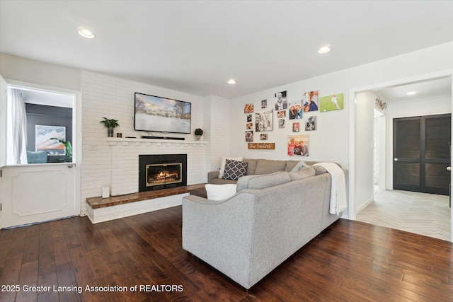 living room with dark hardwood / wood-style flooring and a brick fireplace