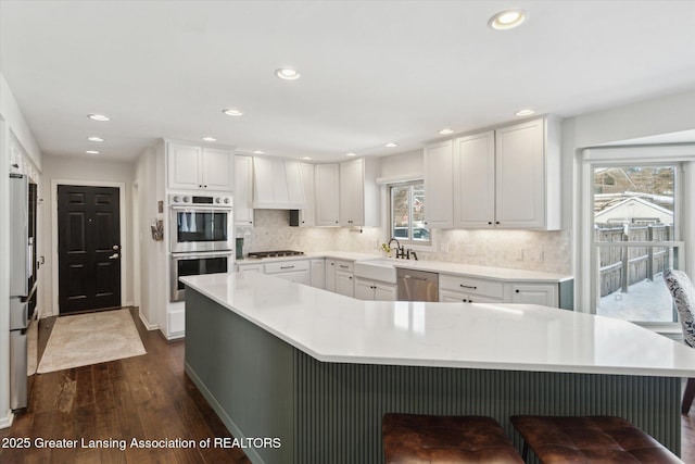 kitchen featuring dark wood-type flooring, white cabinets, tasteful backsplash, and stainless steel appliances