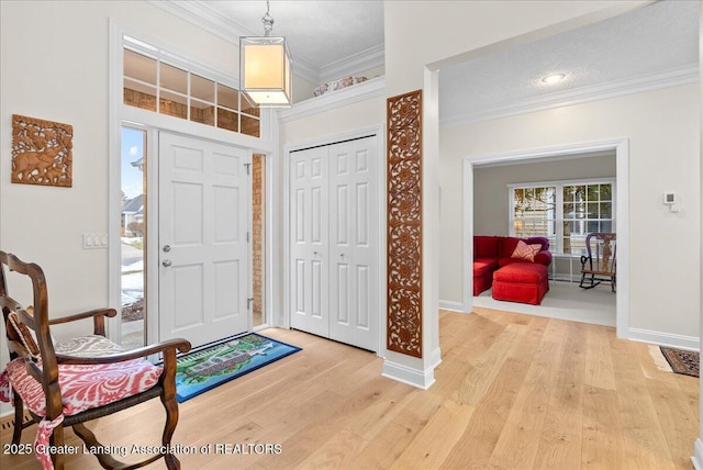 entryway featuring light wood finished floors, baseboards, and ornamental molding