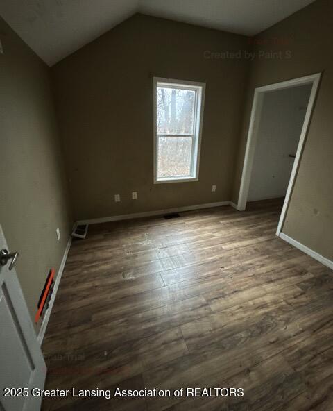 interior space with lofted ceiling, visible vents, dark wood finished floors, and baseboards