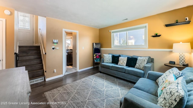 living room with dark wood-style floors, baseboards, stairs, and visible vents