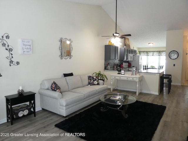 living room featuring high vaulted ceiling, a ceiling fan, baseboards, and dark wood-style flooring