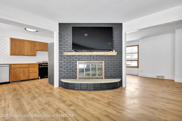 unfurnished living room featuring light wood-type flooring, visible vents, a fireplace, and baseboards