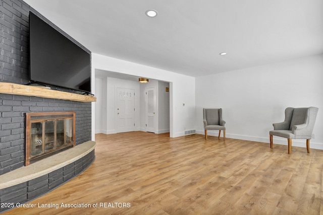 living area featuring light wood-style floors, a fireplace, and baseboards