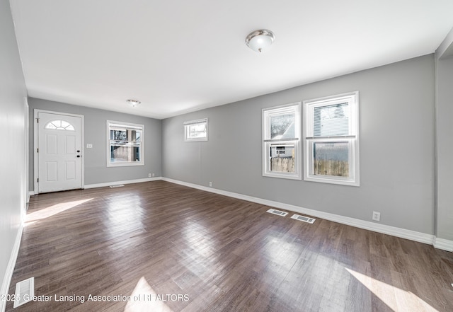 interior space with baseboards, visible vents, and dark wood-type flooring