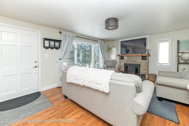 living room featuring a fireplace, baseboards, and wood finished floors