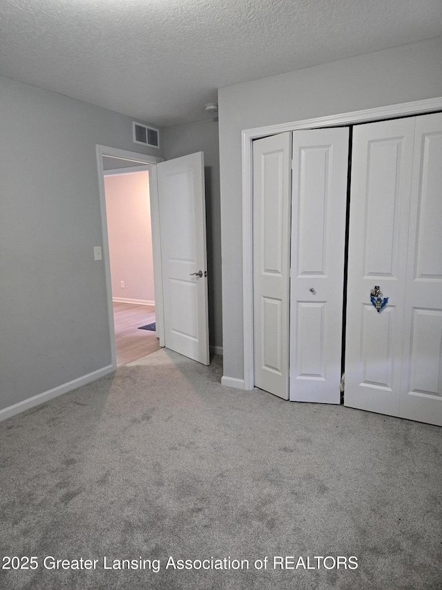 unfurnished bedroom featuring light colored carpet, a closet, visible vents, and baseboards