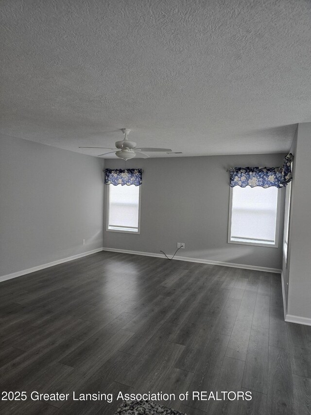 unfurnished room featuring a textured ceiling, baseboards, dark wood finished floors, and a ceiling fan