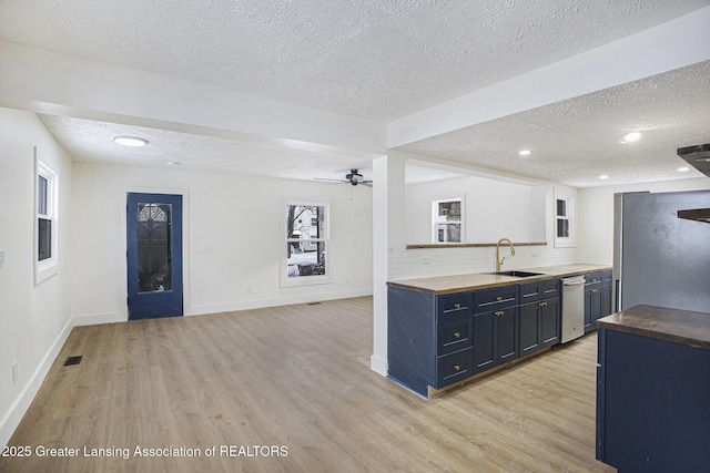 kitchen with light wood finished floors, tasteful backsplash, stainless steel appliances, and a sink