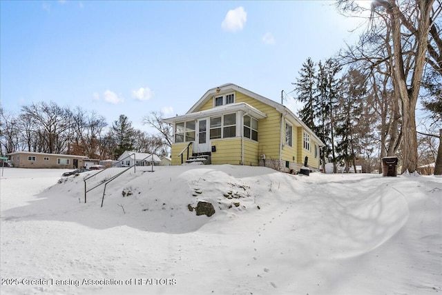 view of snow covered exterior with a sunroom