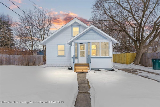 bungalow-style home with entry steps, a sunroom, and fence