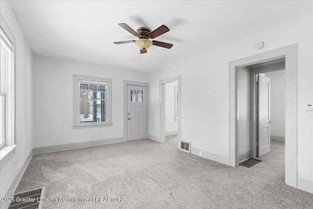 unfurnished room with light carpet, ceiling fan, visible vents, and baseboards