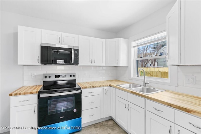 kitchen with tasteful backsplash, appliances with stainless steel finishes, white cabinets, a sink, and wood counters