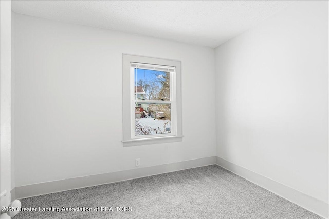 spare room with carpet floors, baseboards, and a textured ceiling