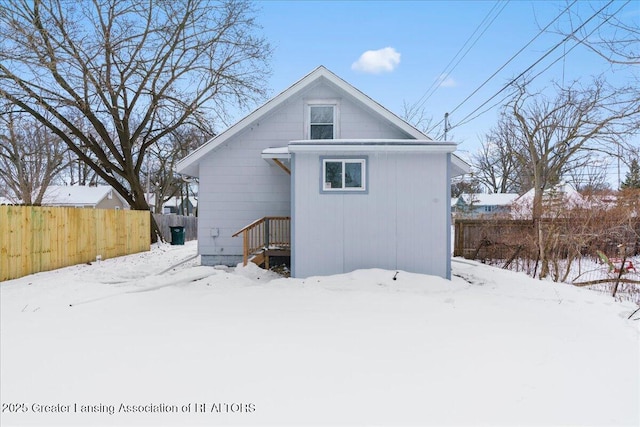 snow covered house featuring fence