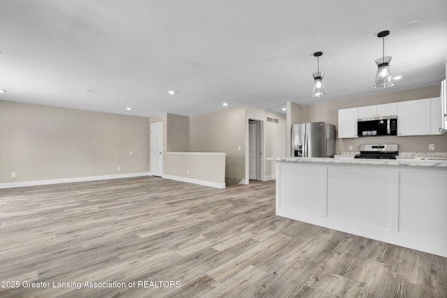 kitchen with light stone counters, decorative light fixtures, appliances with stainless steel finishes, open floor plan, and white cabinets