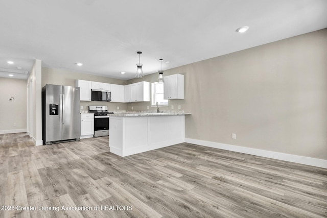 kitchen with stainless steel appliances, a peninsula, a sink, white cabinetry, and decorative light fixtures