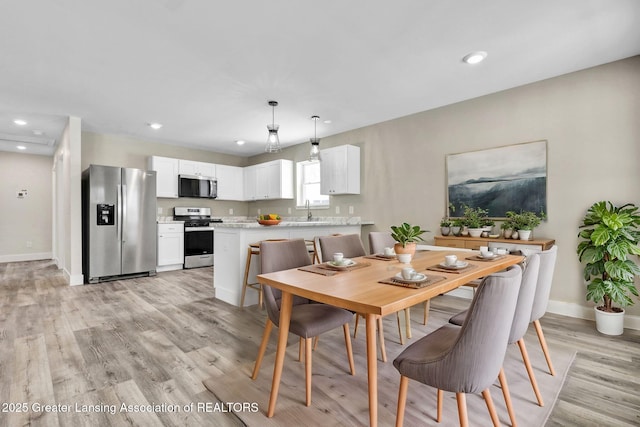 dining room with light wood-style flooring, baseboards, and recessed lighting