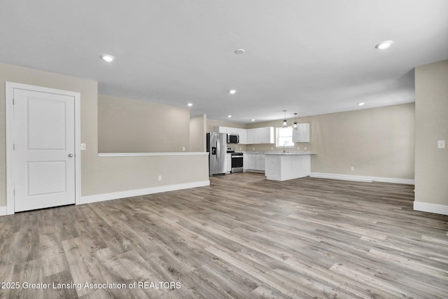 unfurnished living room featuring recessed lighting, light wood-type flooring, and baseboards