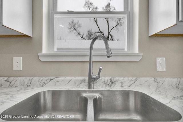 interior details with white cabinetry and a sink