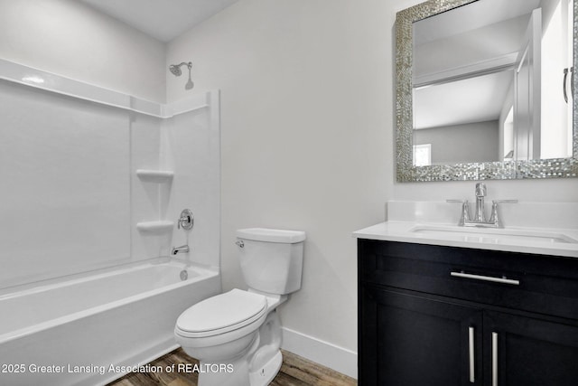 bathroom featuring toilet, wood finished floors, vanity, baseboards, and tub / shower combination