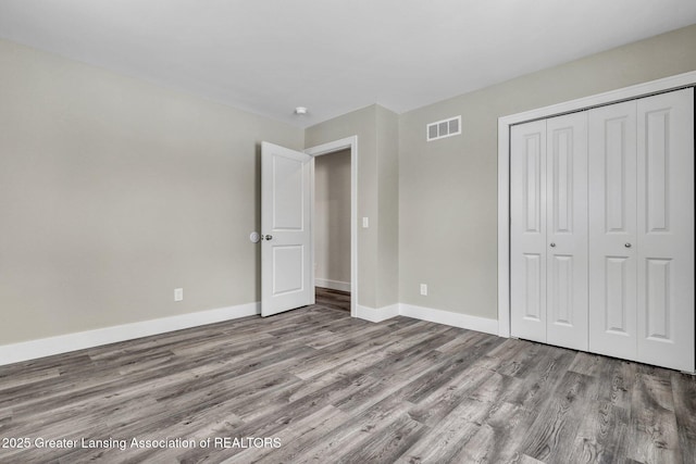 unfurnished bedroom featuring light wood-style flooring, a closet, visible vents, and baseboards