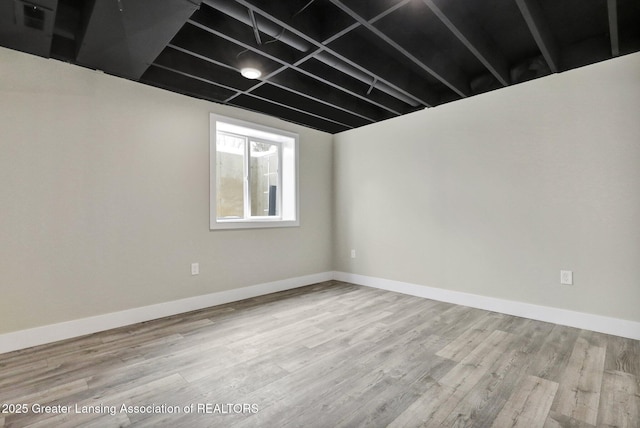 unfurnished room with light wood-type flooring and baseboards