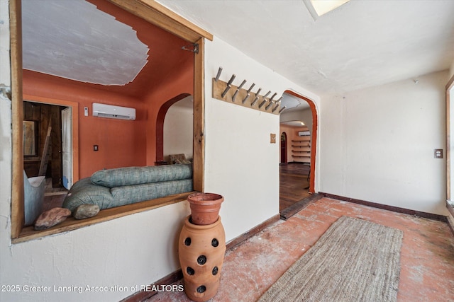 entryway featuring arched walkways, a wall mounted air conditioner, and baseboards