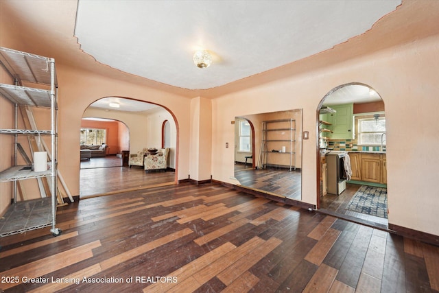 interior space featuring dark wood-style floors, baseboards, and arched walkways