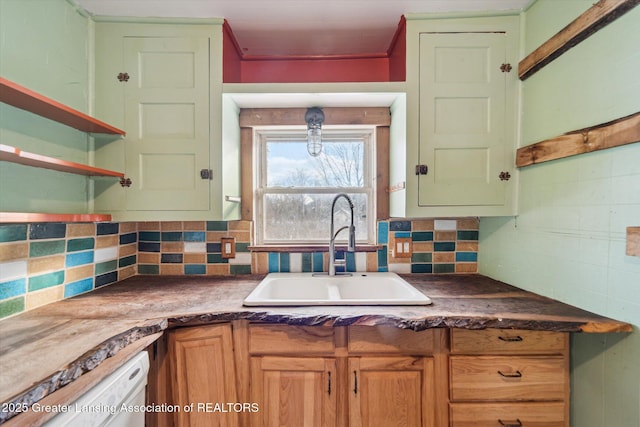 kitchen featuring white dishwasher, a sink, decorative backsplash, open shelves, and dark countertops