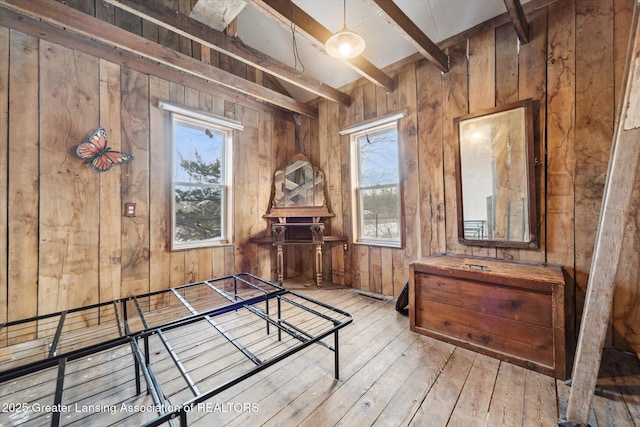 interior space featuring light wood finished floors, wooden walls, and beamed ceiling