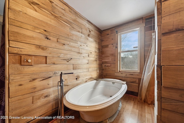 bathroom featuring a freestanding bath, wood finished floors, and wooden walls